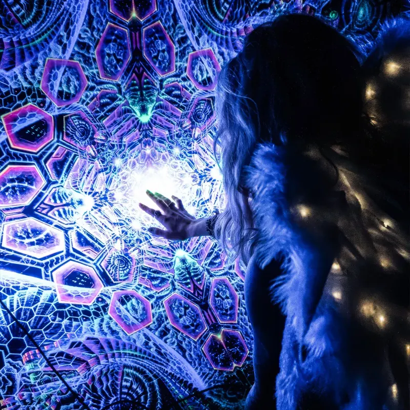 Performer surrounded by illuminated psychedelic artwork